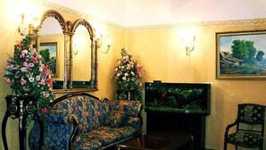 A living room with a floral sofa, a television, a fish tank, and a chair. - Ecoland Hotel (Tallinn)