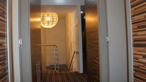 A hallway with a wooden floor and a patterned carpet, leading to a room with a chandelier. - Ecoland Hotel (Tallinn)