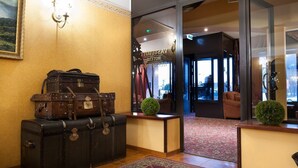 A lobby with vintage suitcases, a reception desk, and a view of the hotel entrance. - Ecoland Hotel (Tallinn)