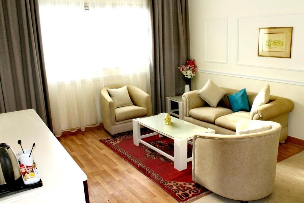 A living room with a sofa, armchairs, a coffee table, a small side table, and a vase with flowers.