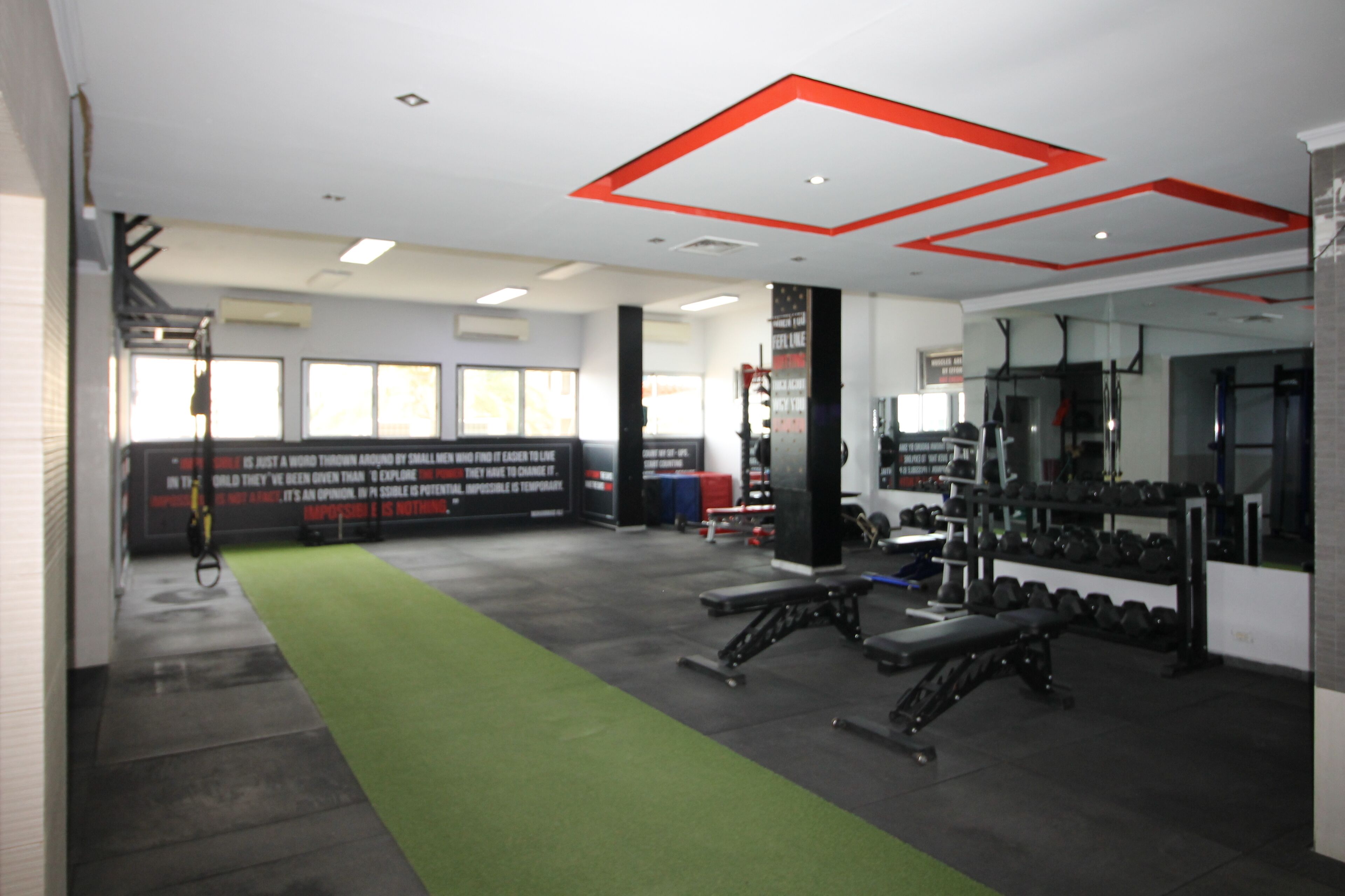 A gym with exercise equipment, a green mat, and motivational posters on the walls.