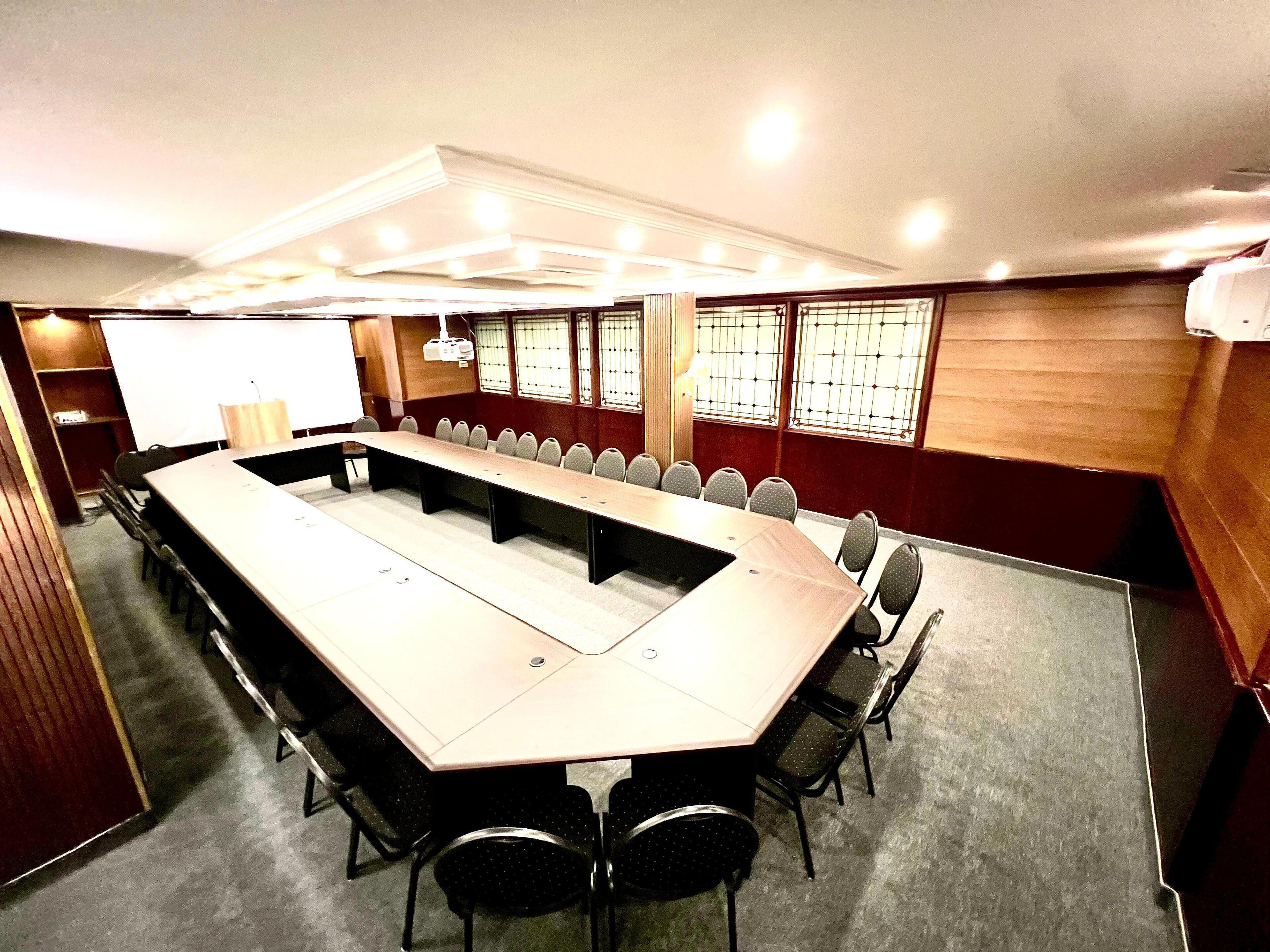 A conference room with a long table, chairs, and a whiteboard.