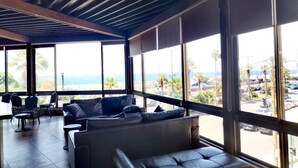 A modern interior with large windows, leather seating, and a view of the ocean. - Hotel Méditerranée Beyrouth  (Beirut)
