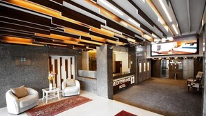 A modern hotel lobby with a reception desk, seating area, and a large television screen. - Hotel Méditerranée Beyrouth  (Beirut)