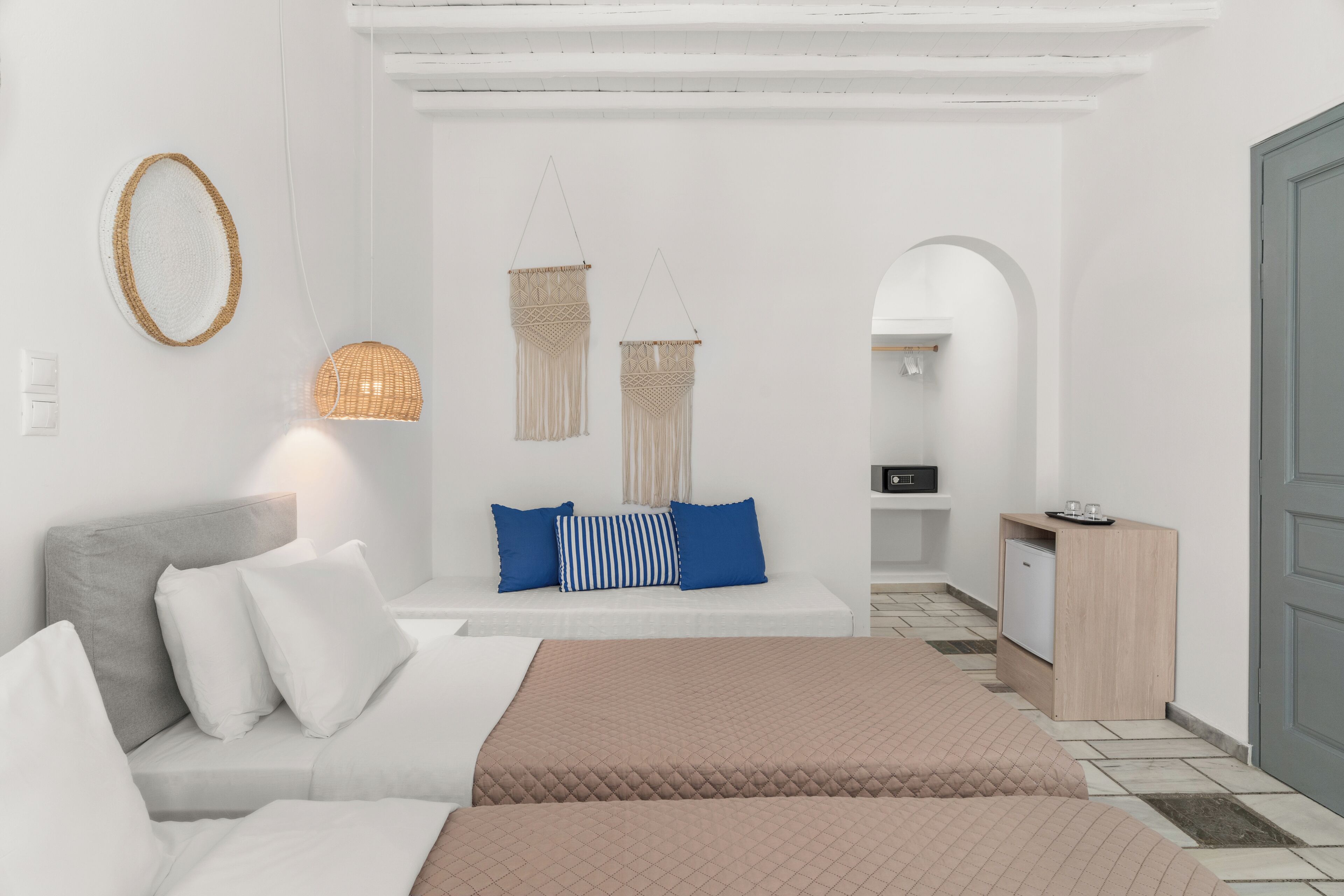 Una habitación de hotel moderna con una cama, un sofá, un escritorio pequeño y una lámpara colgante.
