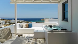 A balcony with a white sofa, a wooden chair, and a hot tub.