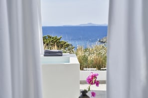 Relax in a serene ocean-view bathroom with a modern bathtub and neatly folded towels.