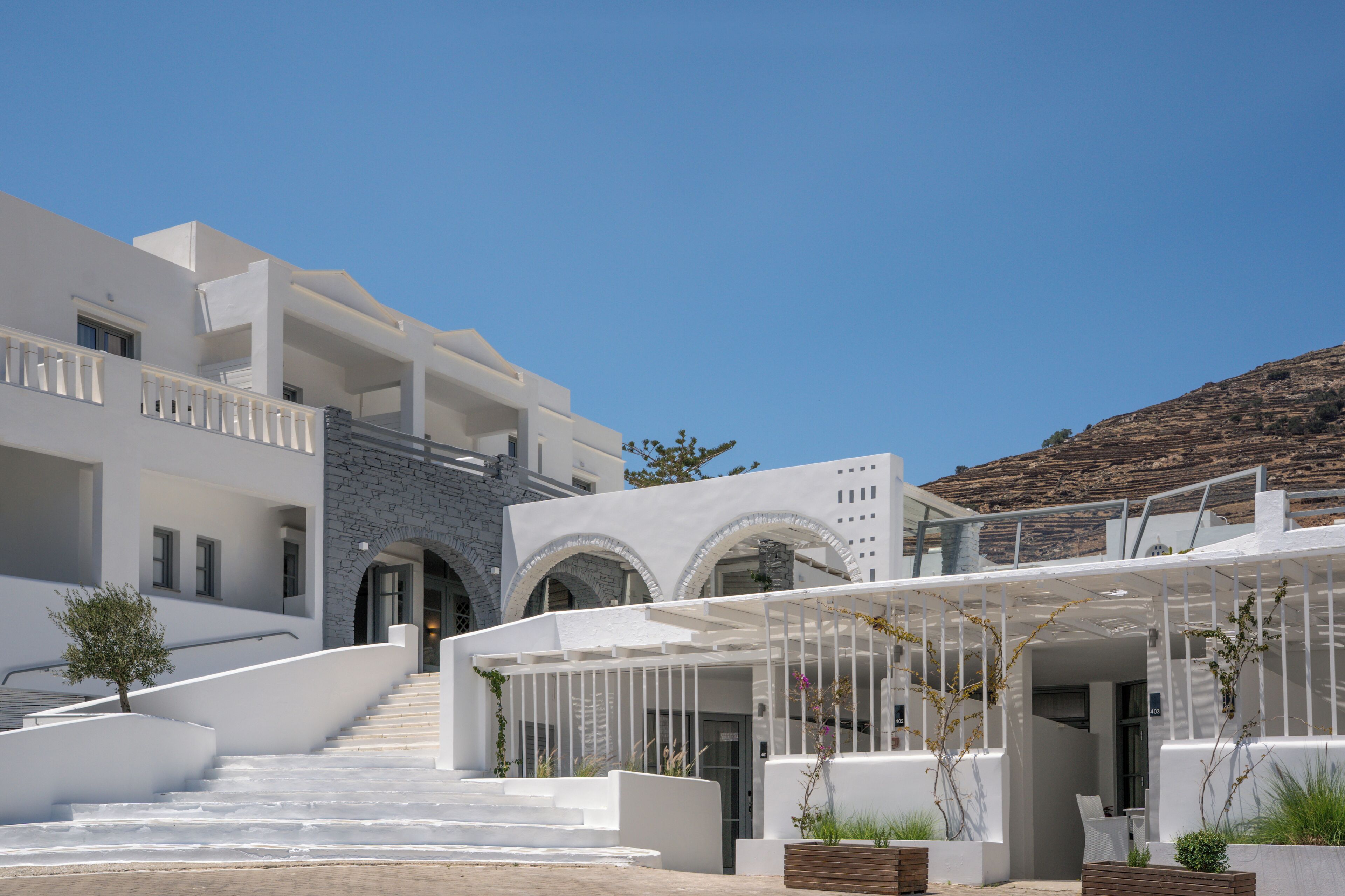 Un hôtel moderne à l’extérieur blanc, avec un escalier menant à l’entrée et offrant une vue sur le paysage environnant.