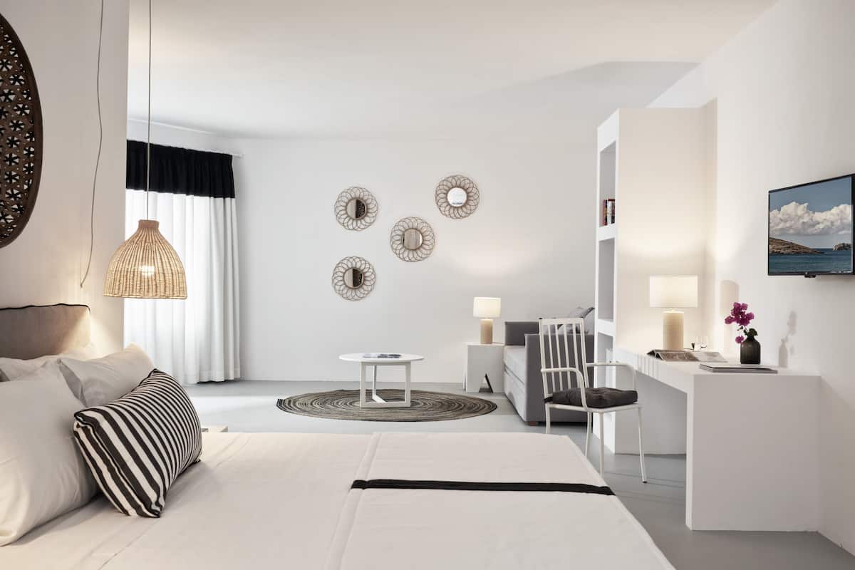 A modern hotel room with a bed, a desk, a chair, and a television.