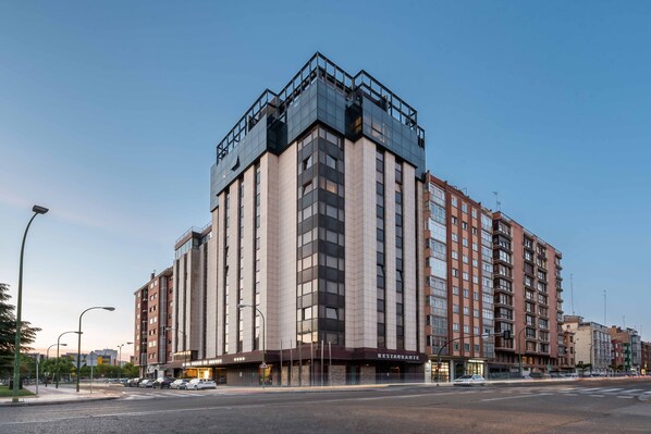 A multi-story hotel with a modern design, featuring a prominent restaurant on the ground floor.