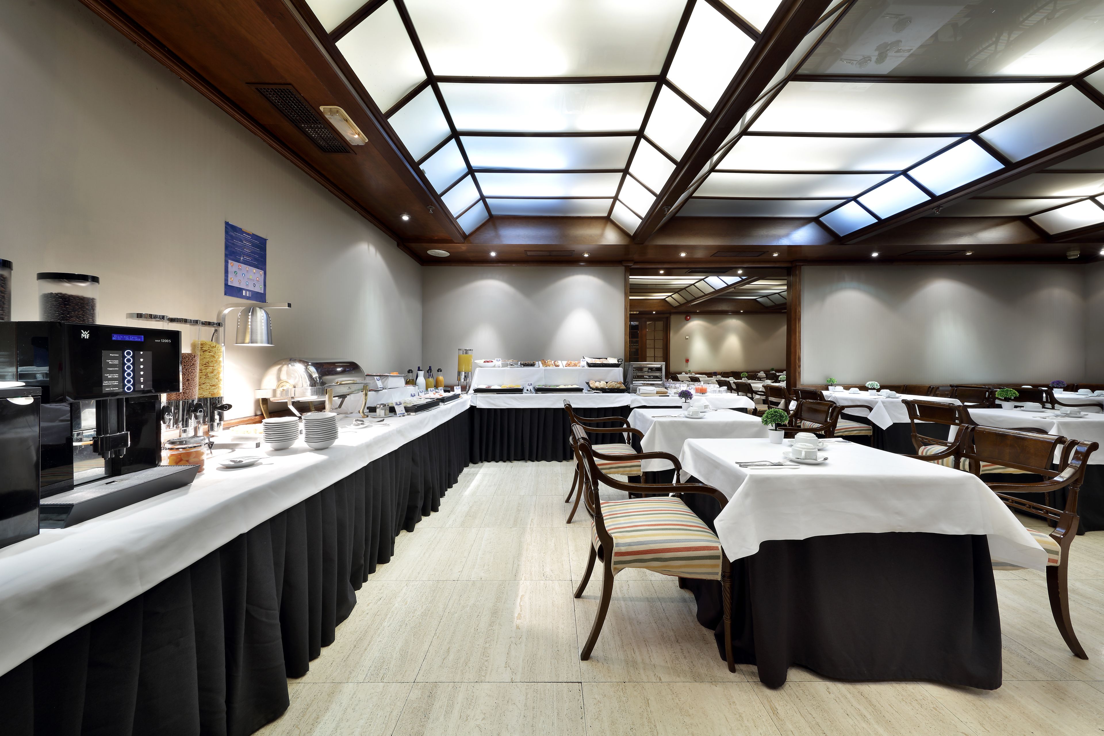 A dining area with a long counter, multiple tables, and chairs.