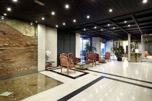 A lobby with a glass floor, wooden chairs, a reception desk, and a large window.