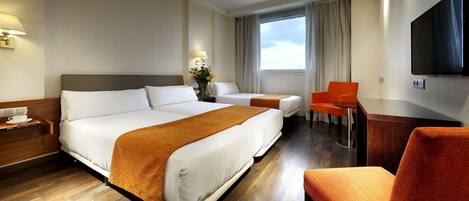 Une chambre d’hôtel avec deux lits, une télévision et un bureau avec une chaise.