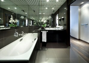 A modern bathroom with a large bathtub, a sink, and a mirror.