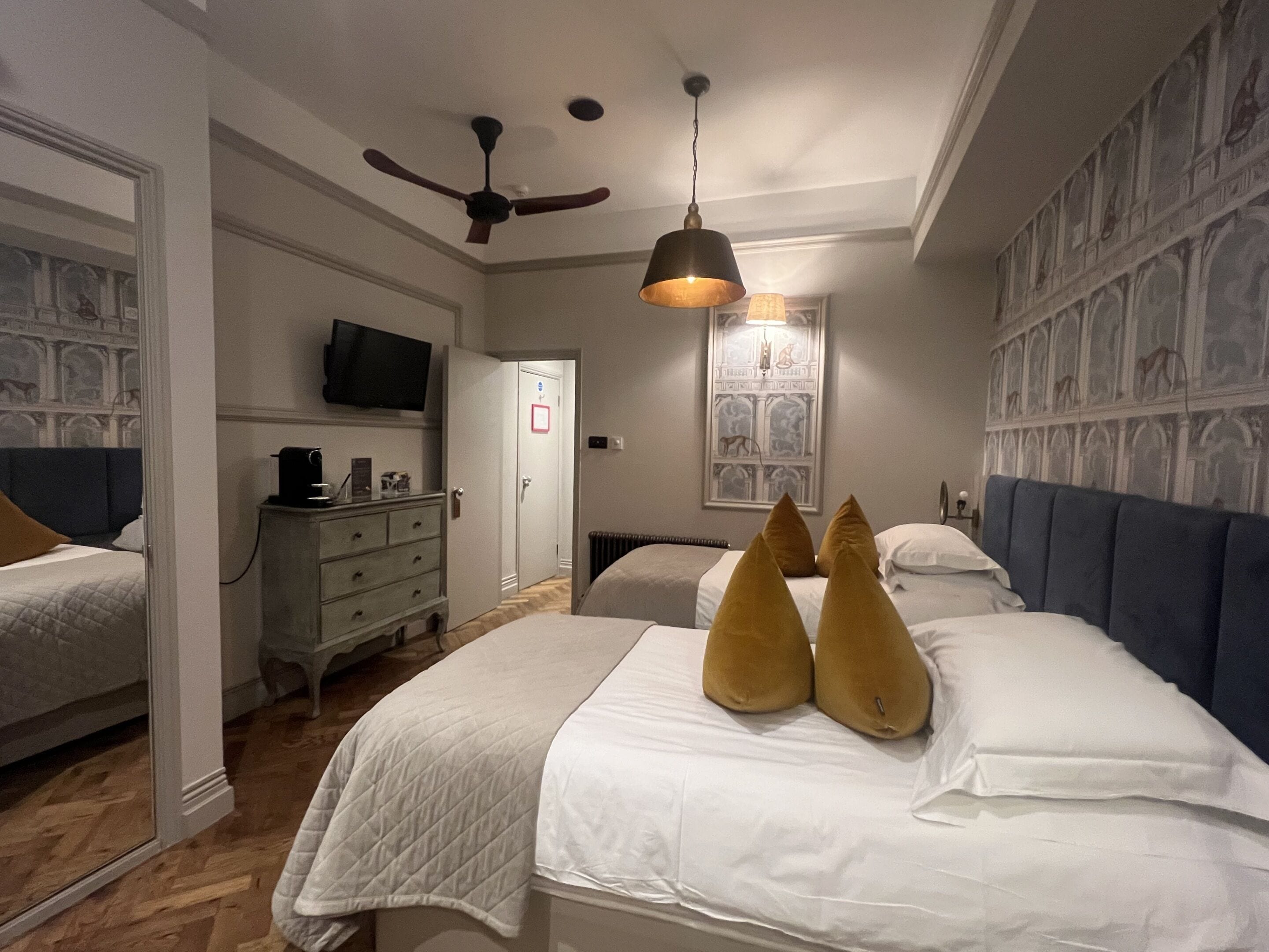 A hotel room with a bed, a dresser, a television, and a ceiling fan.