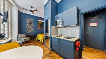 A compact room with a kitchenette, a bed, a chair, and a small table.