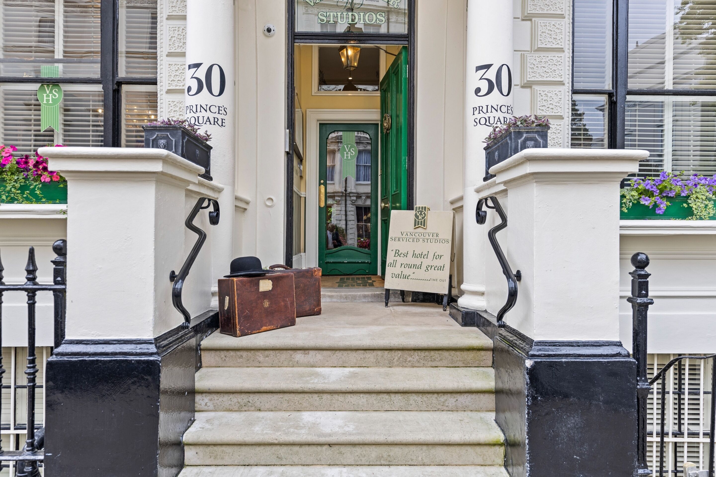A hotel entrance with a sign reading "30 PRINCES SQUARE" and "Vancouver Serviced Studios."