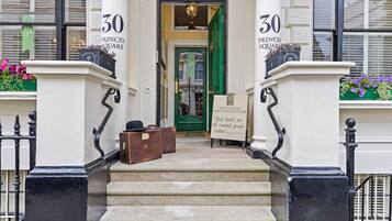 A hotel entrance with a sign reading "30 PRINCES SQUARE" and "Vancouver Serviced Studios."