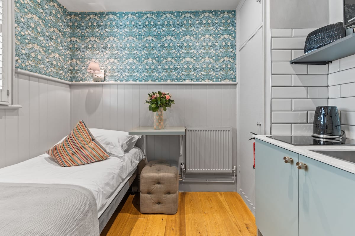 Une chambre à coucher de taille modeste, comprenant un lit, une table de chevet avec un vase et un radiateur.