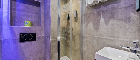 A modern bathroom with a glass-enclosed shower, a white sink, and a toilet.