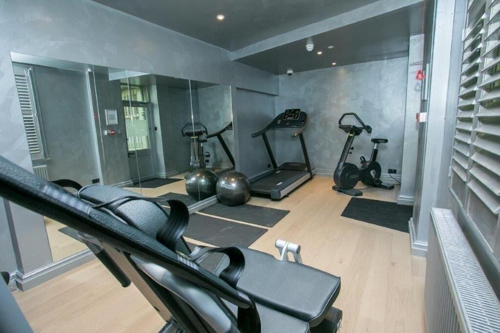 Une salle de sport moderne équipée de matériel d’exercice, dotée d’un miroir et d’un mur en verre.