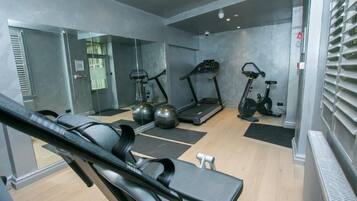 Une salle de sport moderne équipée de matériel d’exercice, dotée d’un miroir et d’un mur en verre.