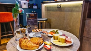 A breakfast setting with croissants, cheese, ham, and a fruit bowl on a wooden table. - Vancouver Studios (London)