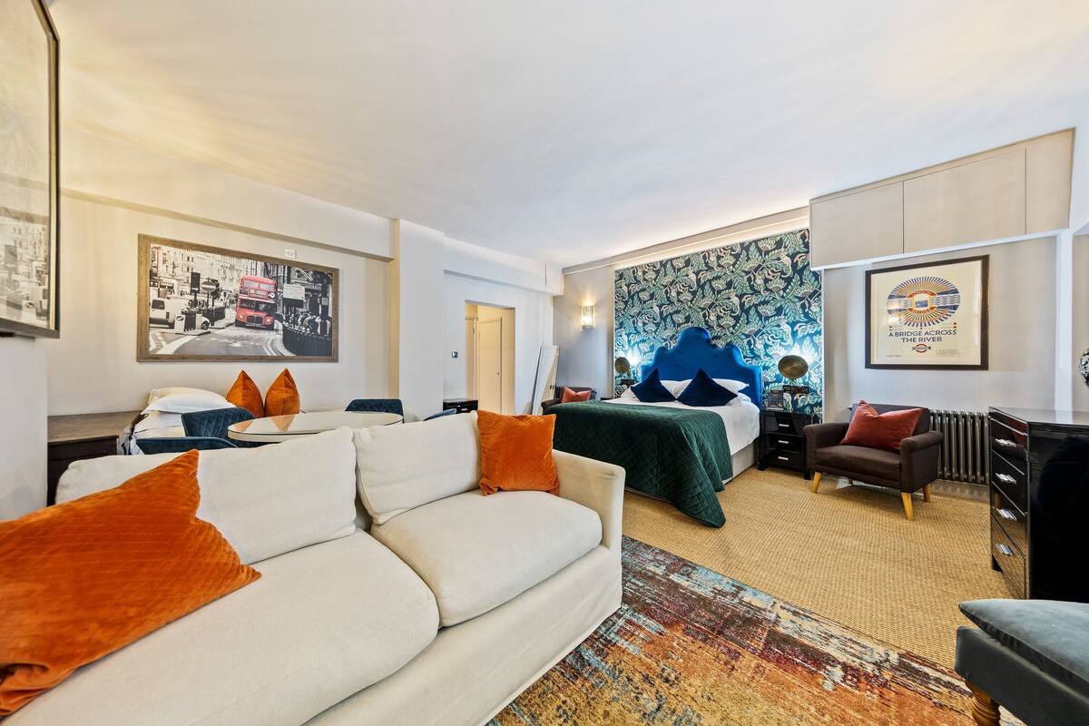 Une chambre d’hôtel avec un canapé, un lit, une chaise et un bureau. Il y a un tableau au mur et un certificat encadré.