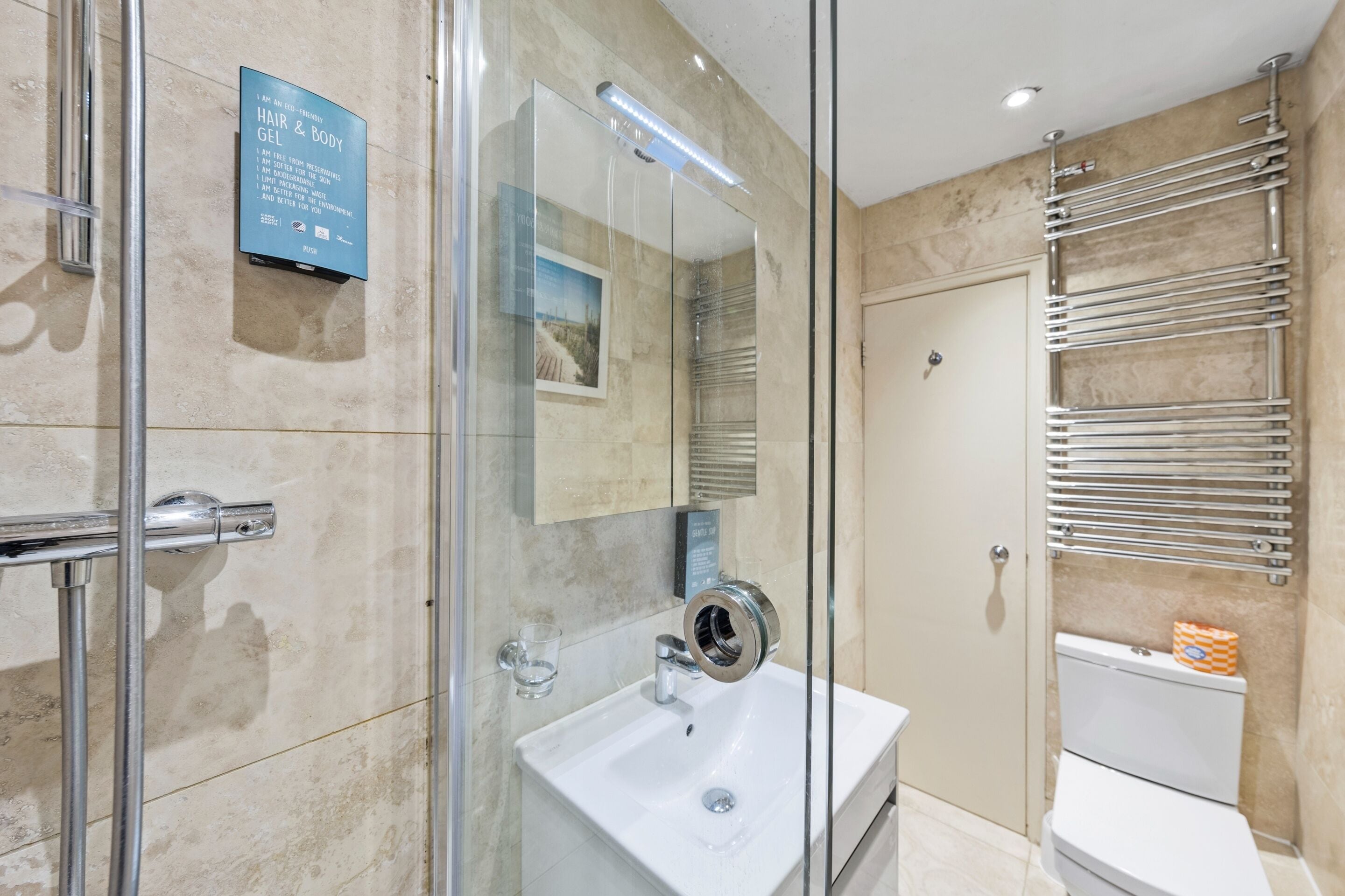 A modern bathroom with a glass shower enclosure, a white sink, and a toilet with a towel rack.
