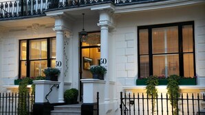 A building with a white facade, black-framed windows, and a balcony with wrought iron railings. - Vancouver Studios (London)