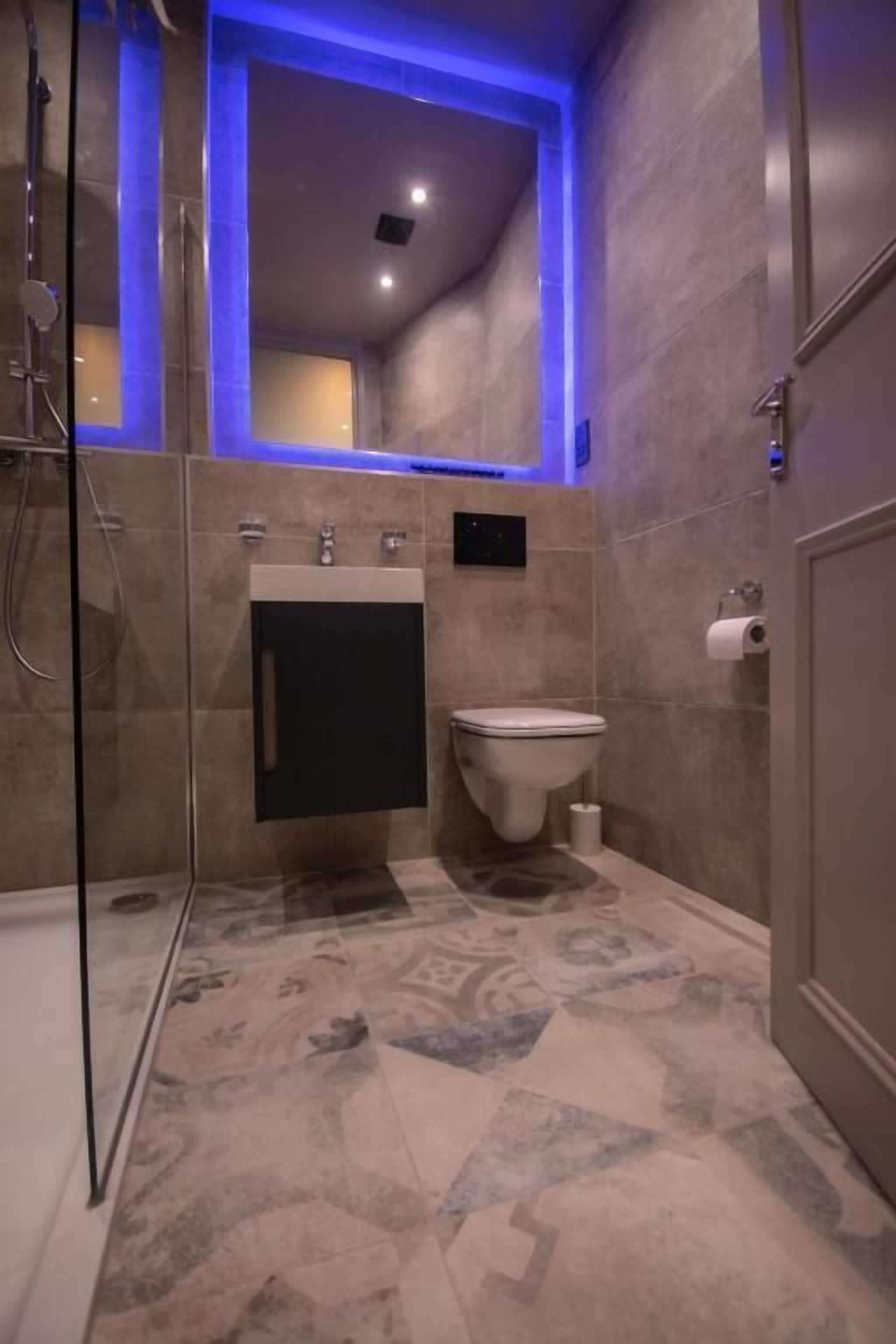 A modern bathroom with a glass shower enclosure, a sink with a black cabinet, and a toilet.