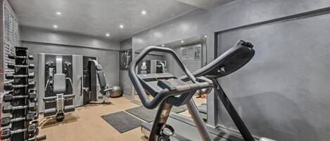 Une salle de sport équipée de tapis de course, d’appareils de musculation et d’haltères.