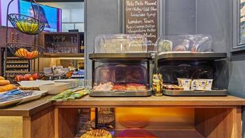 A breakfast buffet with various food items and a menu board listing available beverages.