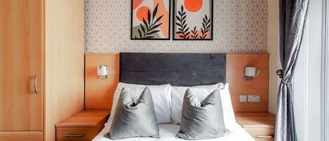 Un dormitorio con una cama, dos mesitas de noche, un armario y dos luces fijadas a la pared.