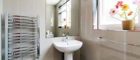 Een badkamer met een wit wastafel, een chroom handdoekhouder en een spiegel.