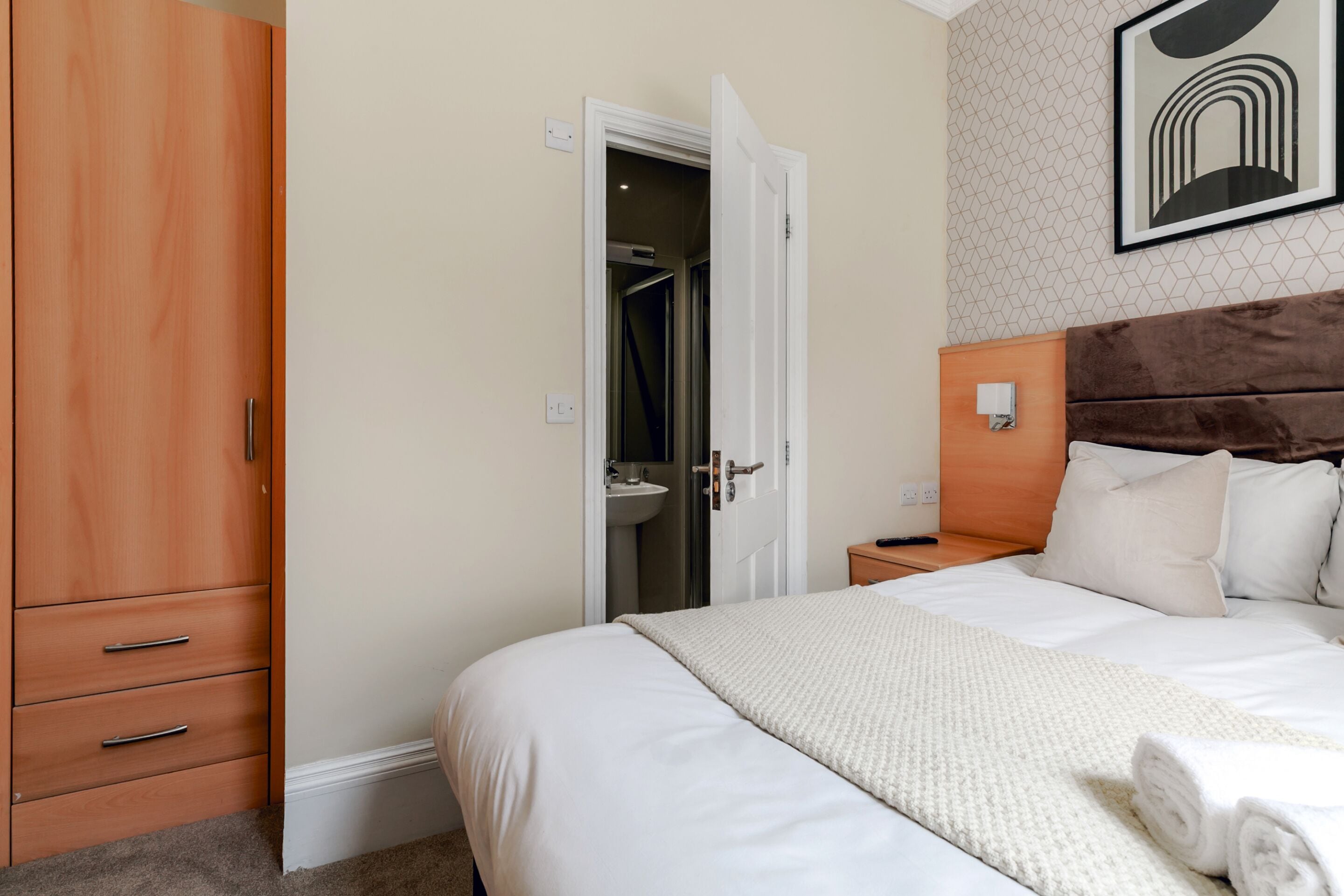 Une chambre à coucher comprenant un lit, une armoire, une salle de bain et une table de chevet.