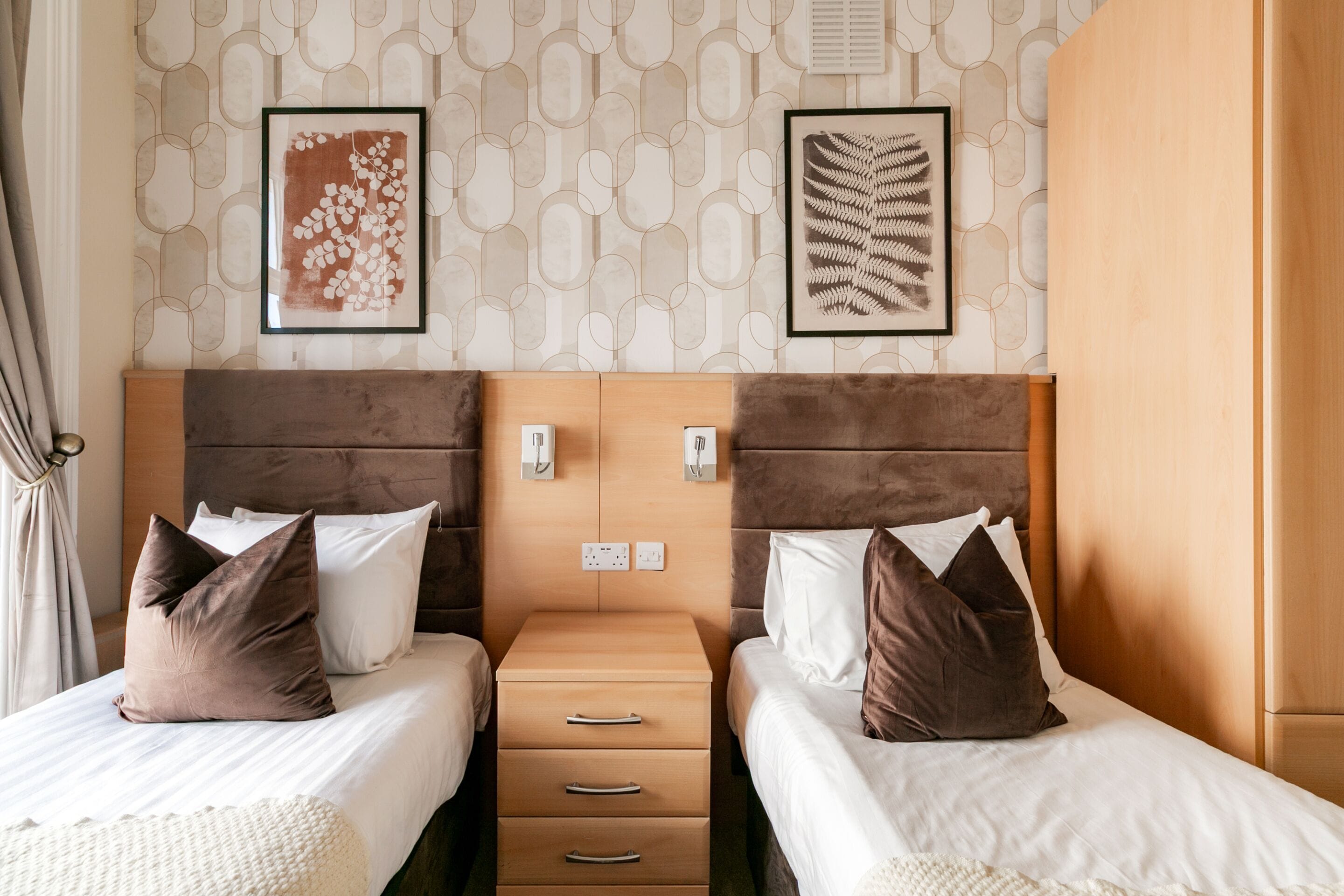 Ein Hotelzimmer mit zwei Betten, einem Holzkopfteil, einem Nachttisch und einem Bild an der Wand.