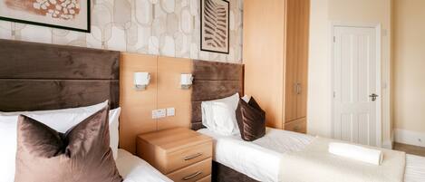 A hotel room with a bed, bedside tables, a wardrobe, and a door.