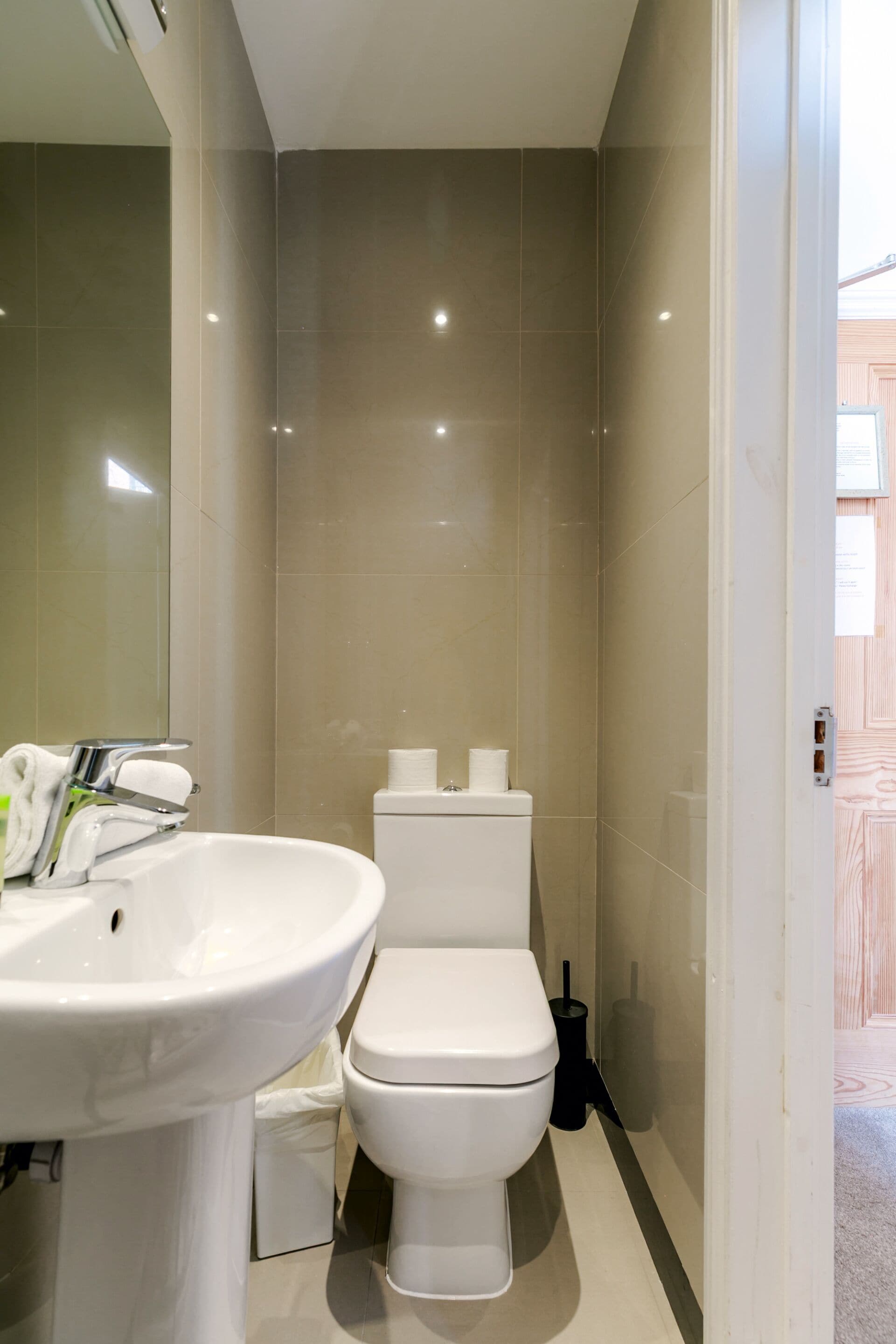 Un bagno con lavandino, WC e specchio bianchi.