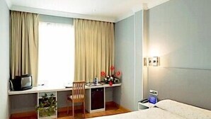 A hotel room with a bed, a desk with a chair, a television, and a window with curtains. - Hotel Faranda Express Las Lomas (Oviedo)
