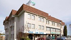 A hotel building with multiple floors, a sign indicating it is a hotel, and several parked cars in front. - Hotel Faranda Express Las Lomas (Oviedo)