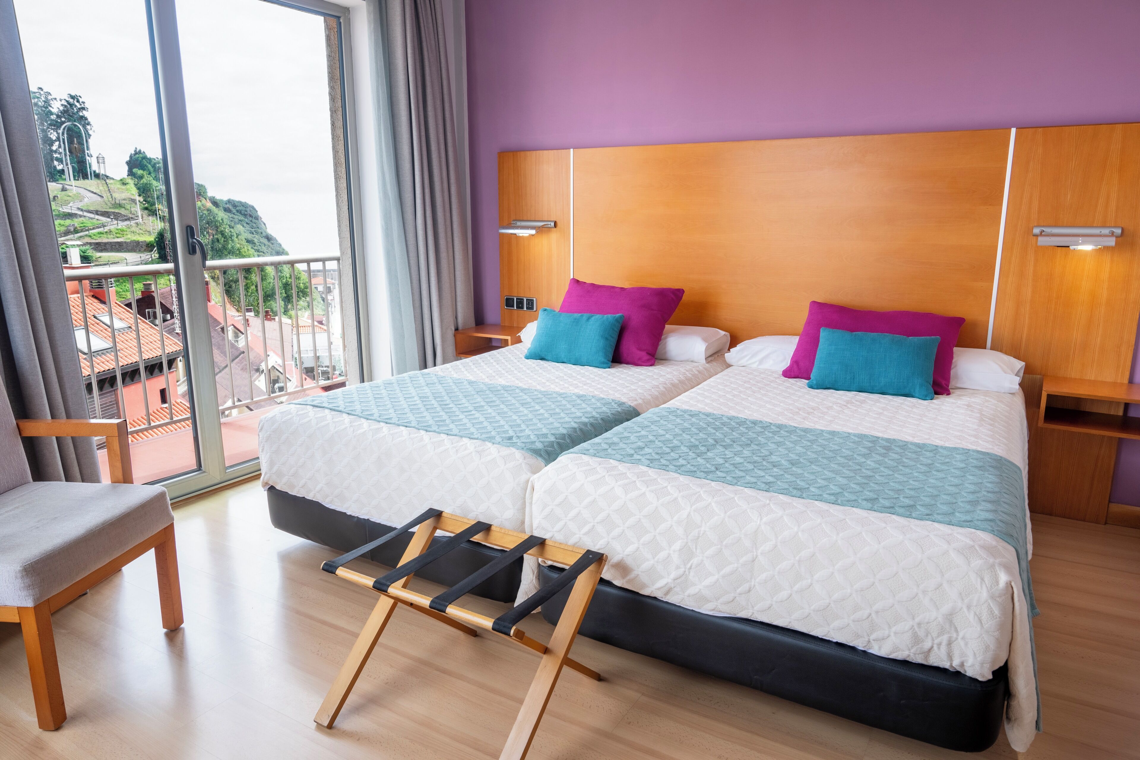 A hotel room with two beds, a balcony, and a view of the city.