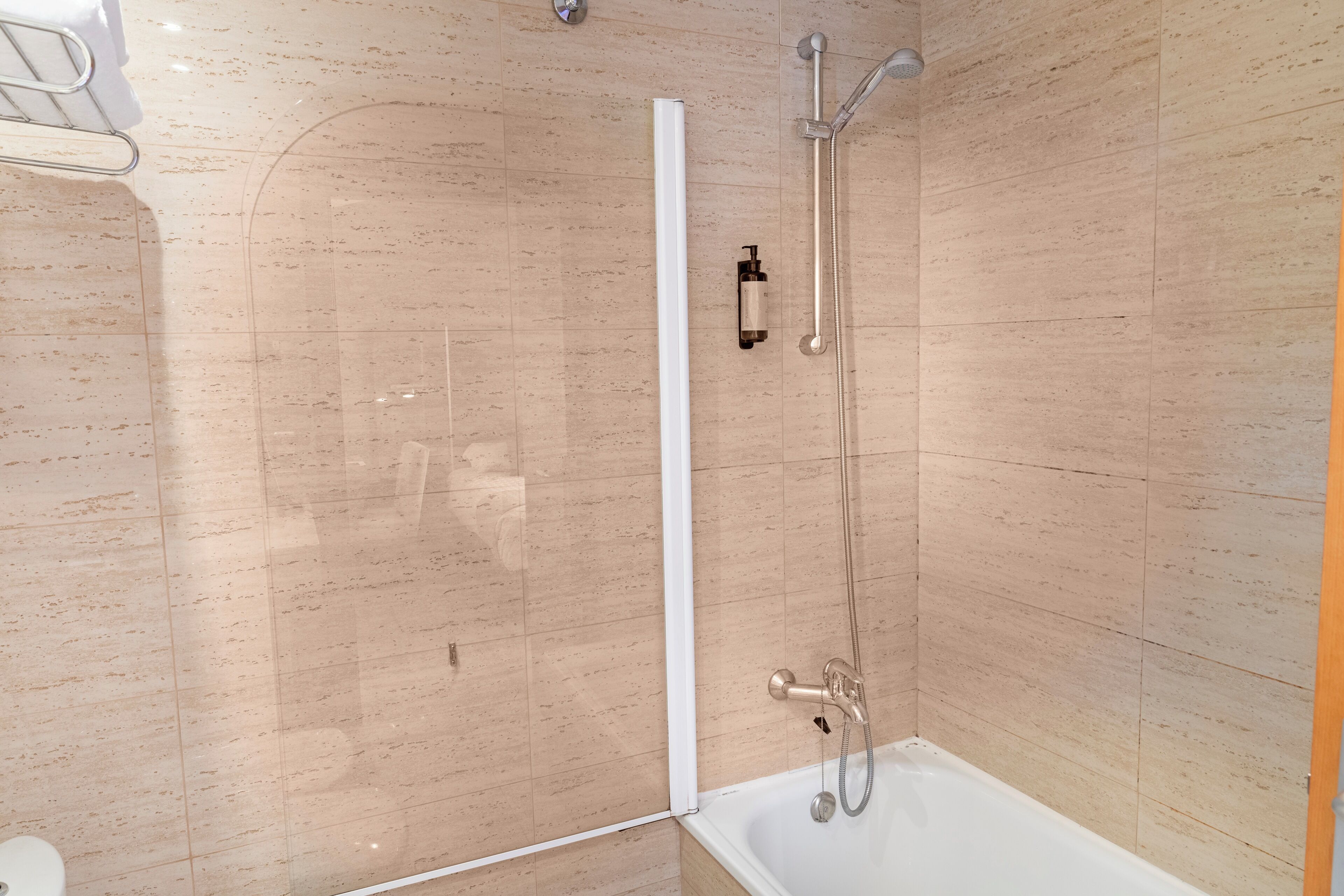 Un baño moderno con ducha de vidrio, bañera blanca y un inodoro.