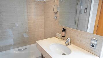 Un baño moderno con un lavamanos blanco, un espejo, un perchero para toallas y una ducha.