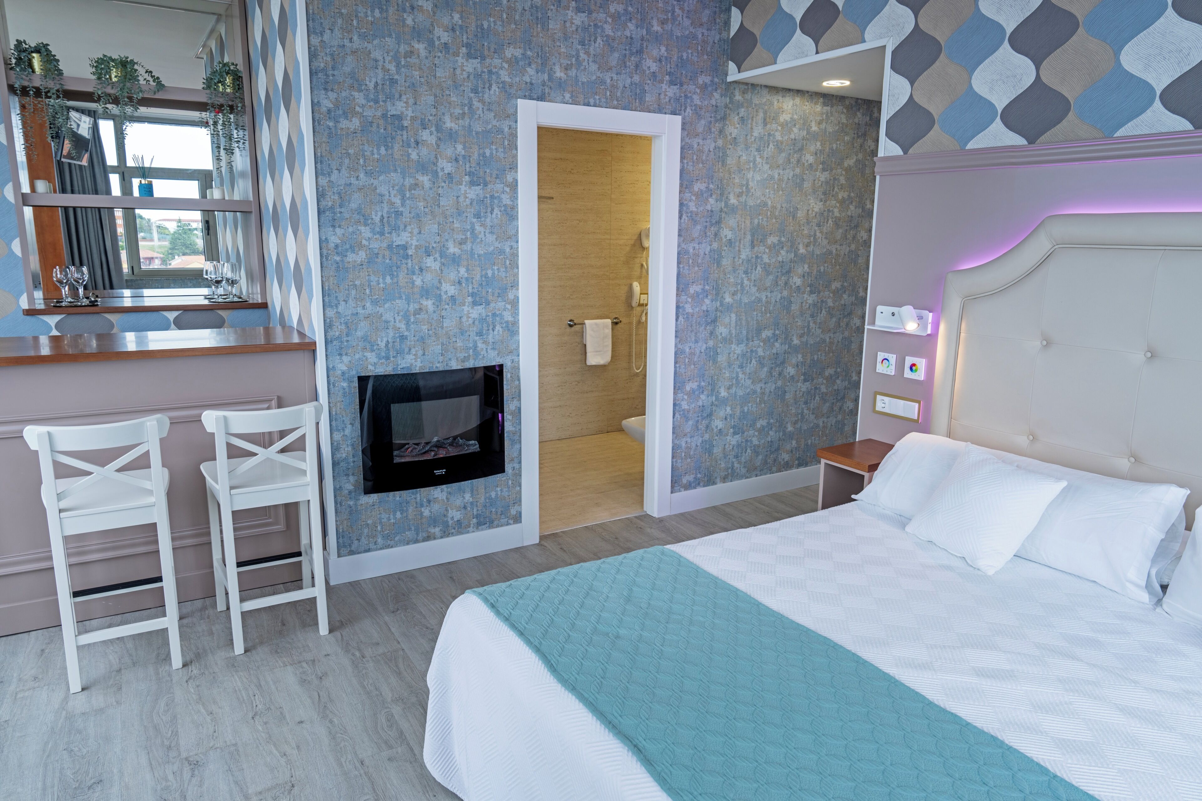 A hotel room with a bed, a TV, a bathroom, and a seating area with chairs.