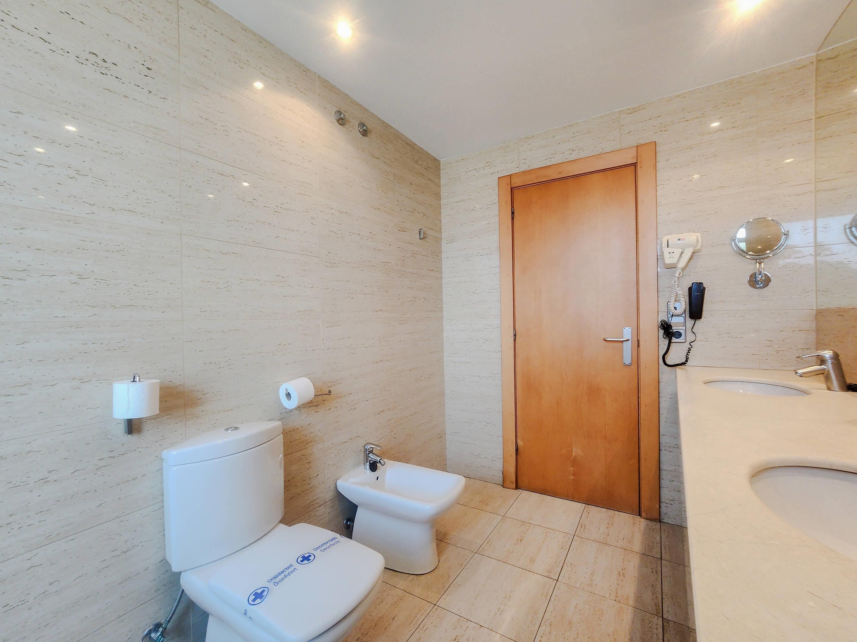 A modern bathroom with a toilet, bidet, and sink.