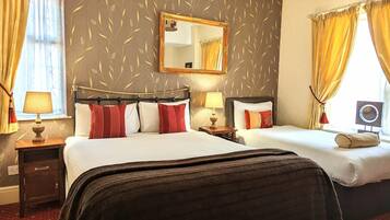 A hotel room with two beds, a large mirror, and a window with curtains.