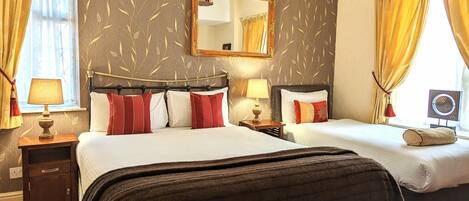 A hotel room with two beds, a large mirror, and a window with curtains.