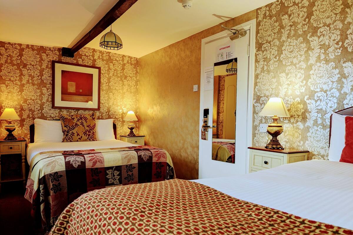 Una habitación de hotel con dos camas, un espejo grande y una puerta con un letrero de '¡Atención!'.
