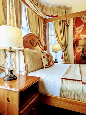A traditional bedroom with a wooden bed, two bedside tables with lamps, and a large window with curtains.